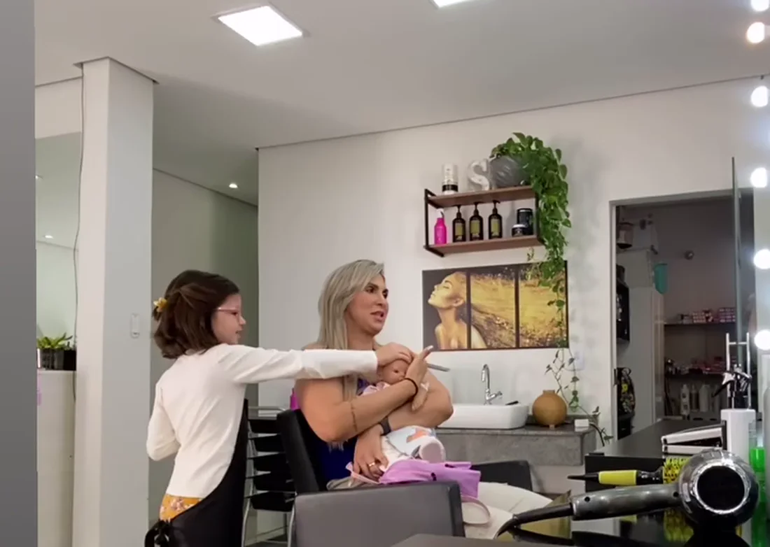 Cliente sendo atendida no salão, com espelhos e plantas ao fundo