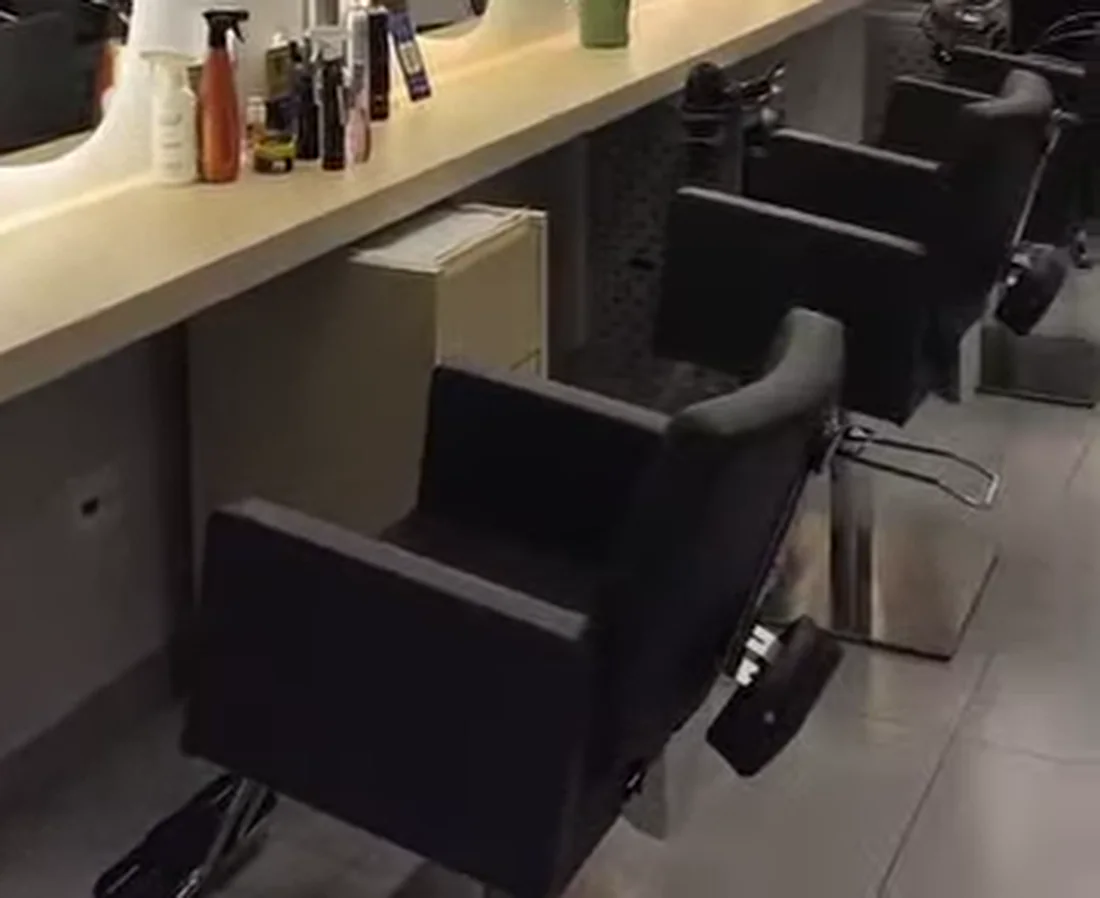 Bancada de atendimento do salão, com espelhos, produtos e cadeiras